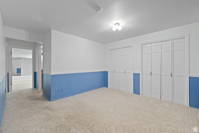 unfurnished bedroom with multiple closets and carpet flooring