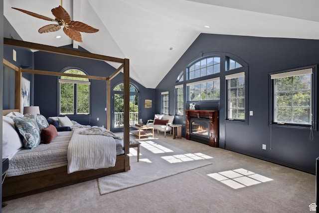 carpeted bedroom with vaulted ceiling, multiple windows, access to outside, a glass covered fireplace, and recessed lighting