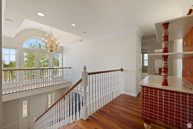 stairway with plenty of natural light, wood finished floors, a chandelier, baseboards, and ornamental molding