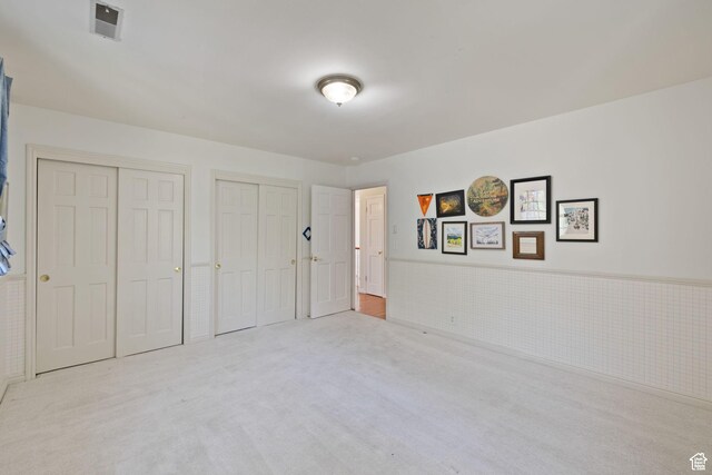 unfurnished bedroom with multiple closets and carpet flooring