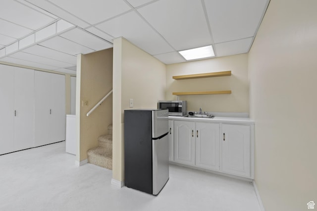 kitchen featuring stainless steel microwave, refrigerator, a sink, open shelves, and white cabinetry