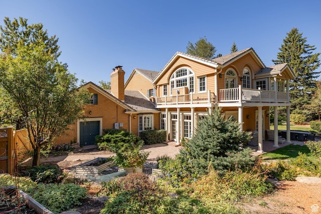 back of property featuring a vegetable garden, a balcony, a patio area, brick siding, and fence