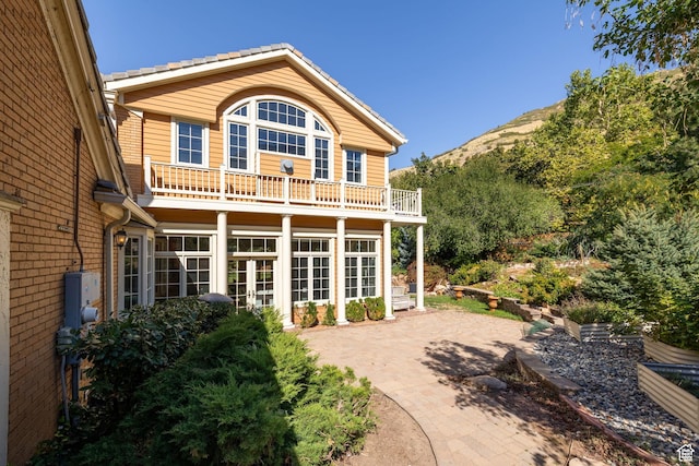 back of house featuring a balcony, a mountain view, and french doors