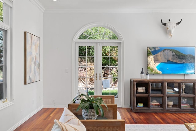 living area with crown molding, wood finished floors, baseboards, and french doors