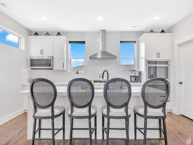 1374 Gambel Oak Way, Park City, UT 84098 - kitchen featuring stainless steel appliances, wall chimney exhaust hood, a center island with sink, tasteful backsplash, and white cabinetry