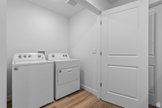 washroom with independent washer and dryer, light wood-style floors, and baseboards
