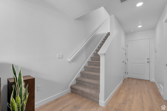 stairway with baseboards, wood finished floors, and recessed lighting