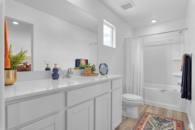 full bathroom featuring toilet, wood finished floors, vanity, shower / bath combo, and recessed lighting
