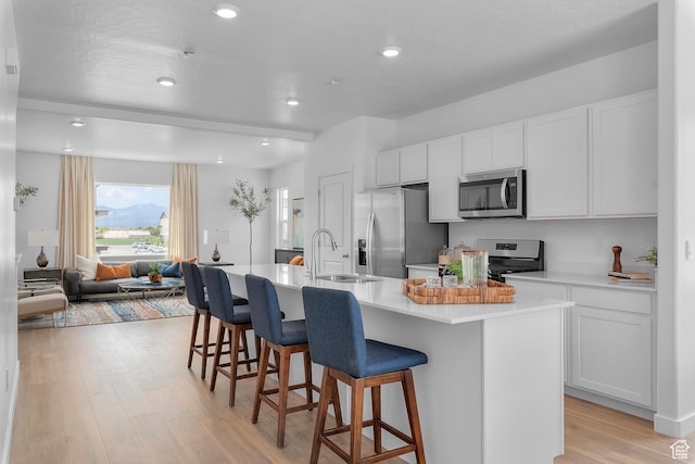 kitchen featuring appliances with stainless steel finishes, a sink, a kitchen bar, an island with sink, and recessed lighting