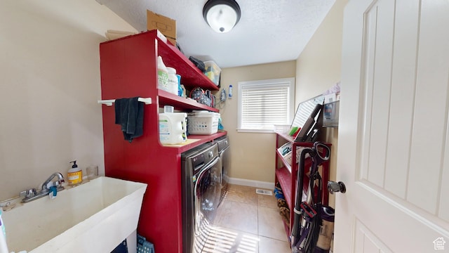 laundry room featuring washing machine and dryer, light tile patterned floors, and baseboards