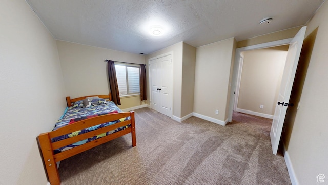 bedroom with a textured ceiling, carpet floors, and baseboards