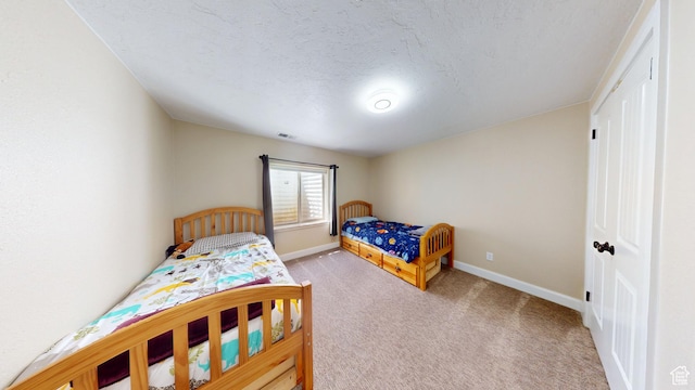 bedroom with carpet flooring, baseboards, and a textured ceiling