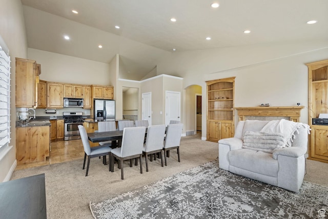 dining space with arched walkways, light colored carpet, recessed lighting, high vaulted ceiling, and baseboards