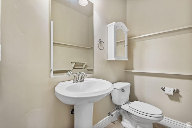 bathroom featuring toilet, baseboards, and a sink
