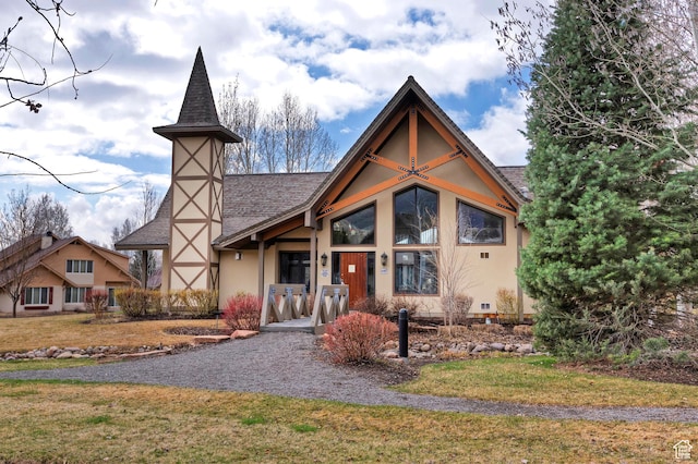 view of front facade featuring stucco siding, a front yard, and roof with shingles