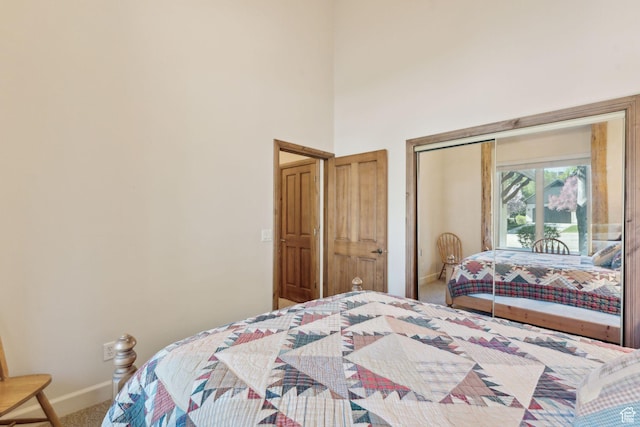 carpeted bedroom featuring baseboards, access to outside, and a towering ceiling