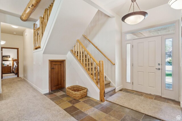 foyer with stone tile floors, stairway, and baseboards