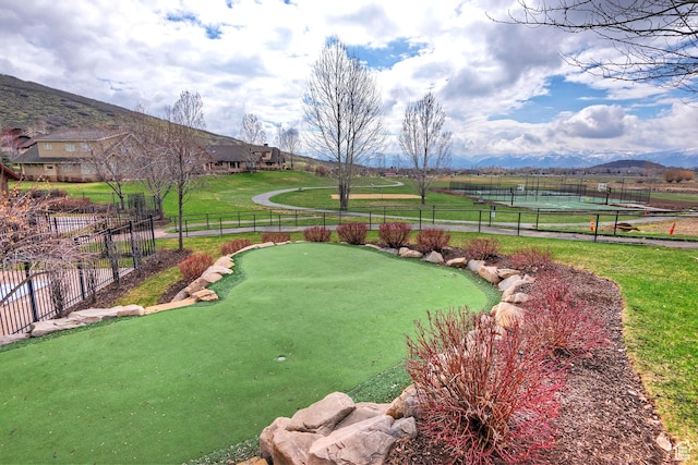 view of yard featuring a putting green, fence, and a mountain view