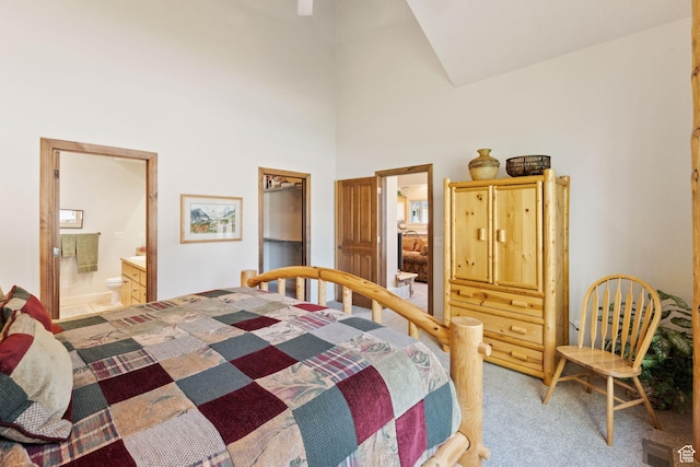 bedroom featuring light carpet, a high ceiling, and connected bathroom