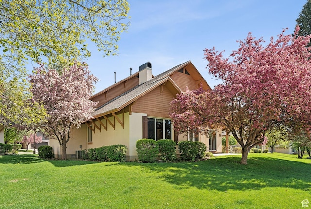view of side of property with a lawn, a chimney, stucco siding, and roof with shingles