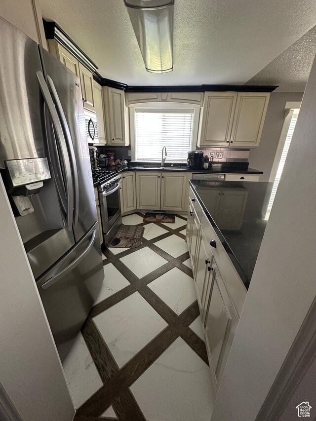 250 W 100 S, Duchesne, UT 84021 - kitchen with stainless steel appliances, dark countertops, a textured ceiling, a sink, and inlaid floor details