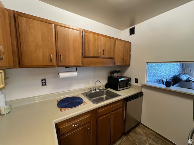 kitchen with appliances with stainless steel finishes, light countertops, a sink, and brown cabinets