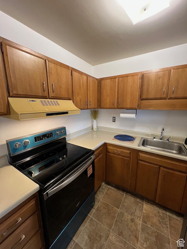 kitchen with black / electric stove, under cabinet range hood, a sink, and light countertops