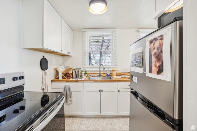 kitchen featuring stainless steel appliances, a sink, white cabinetry, light countertops, and light tile patterned floors