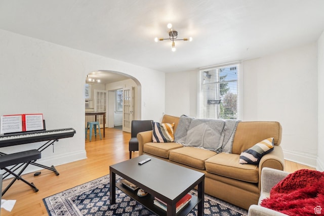 living room with arched walkways, light wood-style floors, and baseboards