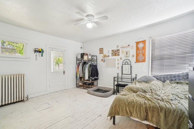 bedroom with radiator heating unit, hardwood / wood-style floors, and ceiling fan