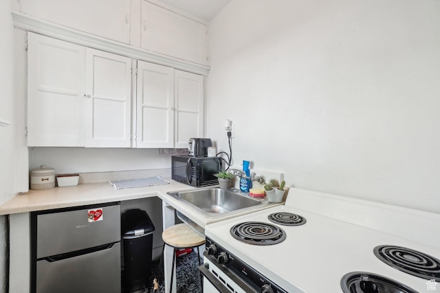 kitchen with white electric range, freestanding refrigerator, white cabinets, and black microwave