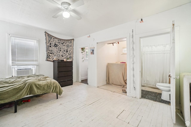 bedroom featuring cooling unit, connected bathroom, and wood finished floors