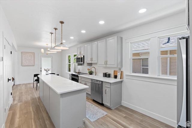 328 E Hampton Ave S, Salt Lake City, UT 84111 - kitchen featuring appliances with stainless steel finishes, a kitchen island, light wood-style flooring, gray cabinetry, and decorative light fixtures