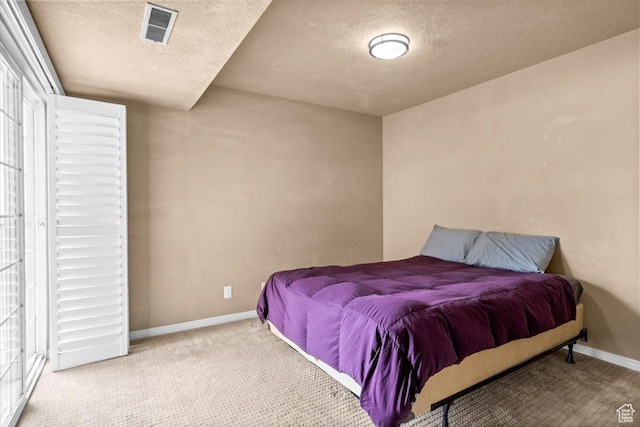 carpeted bedroom with a textured ceiling and baseboards