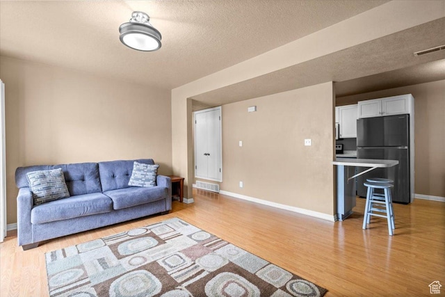 living room with light wood-style floors, baseboards, and a textured ceiling