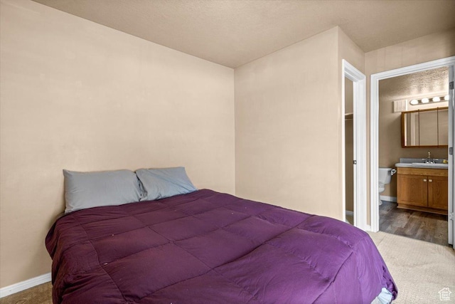 bedroom with carpet floors, a sink, baseboards, and connected bathroom