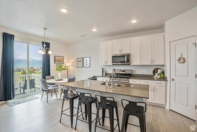 7881 S Highlandpoint Way, West Jordan, UT 84081 - kitchen featuring stainless steel appliances, a sink, light wood finished floors, a breakfast bar, and a chandelier
