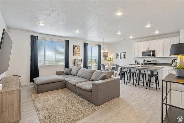 7881 S Highlandpoint Way, West Jordan, UT 84081 - living area with a textured ceiling, light wood finished floors, recessed lighting, and baseboards