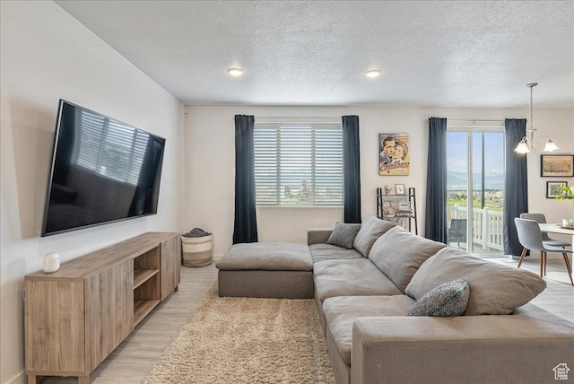 7881 S Highlandpoint Way, West Jordan, UT 84081 - living room with a chandelier, healthy amount of natural light, light wood finished floors, and a textured ceiling