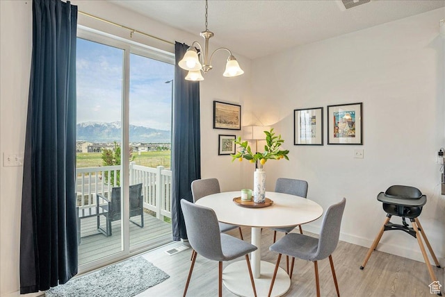 7881 S Highlandpoint Way, West Jordan, UT 84081 - dining area with light wood-style flooring, a chandelier, a mountain view, and baseboards