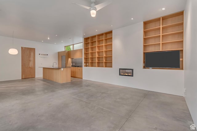 608 S 400 E, Salt Lake City, UT 84111 - unfurnished living room featuring finished concrete floors, built in features, a sink, ceiling fan, and a glass covered fireplace