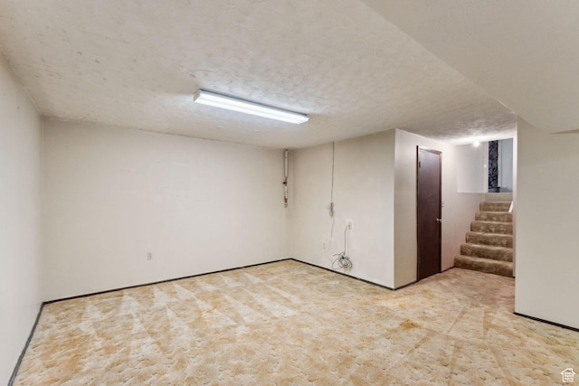 finished below grade area with light colored carpet, stairway, and a textured ceiling