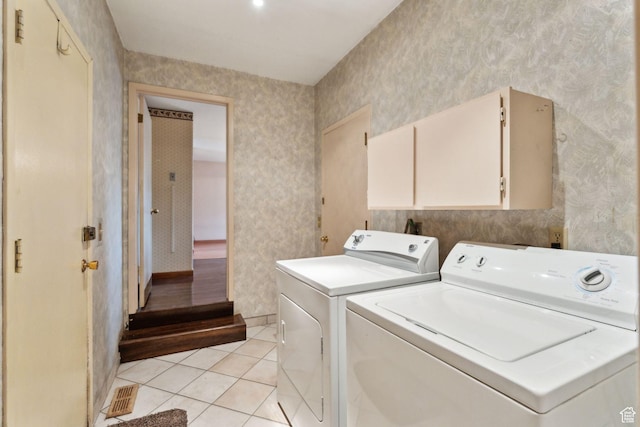 laundry area featuring wallpapered walls, washing machine and dryer, cabinet space, and light tile patterned floors