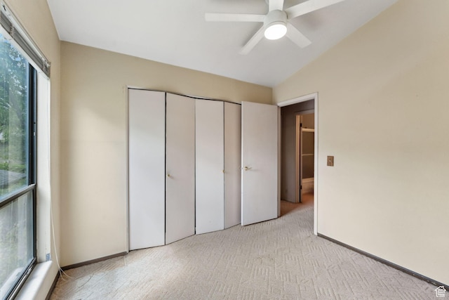 unfurnished bedroom featuring carpet flooring, vaulted ceiling, a closet, baseboards, and a ceiling fan