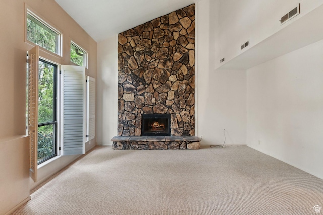 unfurnished living room featuring carpet, a stone fireplace, and high vaulted ceiling