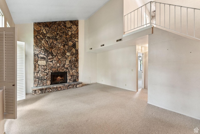 unfurnished living room with carpet floors, a high ceiling, and a fireplace