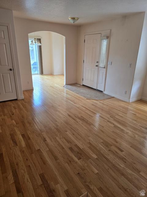 834 N Sapphire St, Morgan, UT 84050 - unfurnished living room featuring arched walkways, light wood finished floors, and baseboards