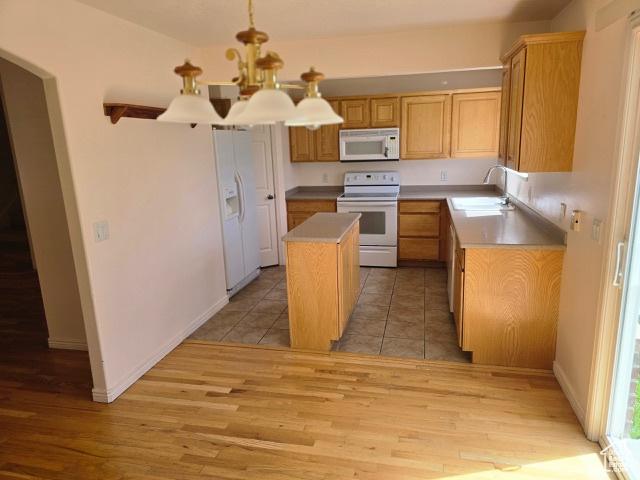 834 N Sapphire St, Morgan, UT 84050 - kitchen featuring white appliances, a sink, a chandelier, light wood finished floors, and a kitchen island