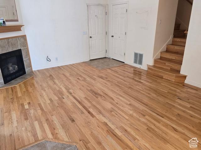 834 N Sapphire St, Morgan, UT 84050 - unfurnished living room featuring wood finished floors, stairs, a tiled fireplace, and baseboards