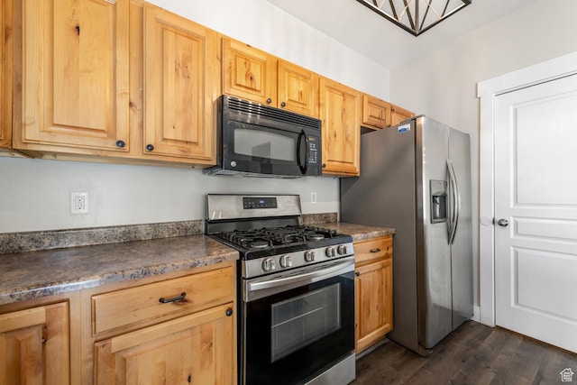 kitchen with stainless steel appliances, dark wood-style floors, dark countertops, and light brown cabinets